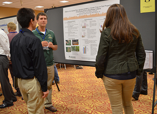 Three People Speak in Front of a Cereal Rye Cover Crops Poster