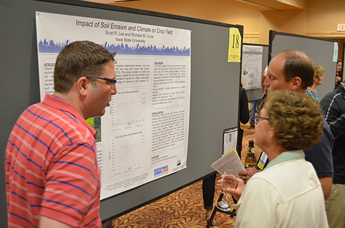 Three People Discuss a Poster Concerning Soil Erosion